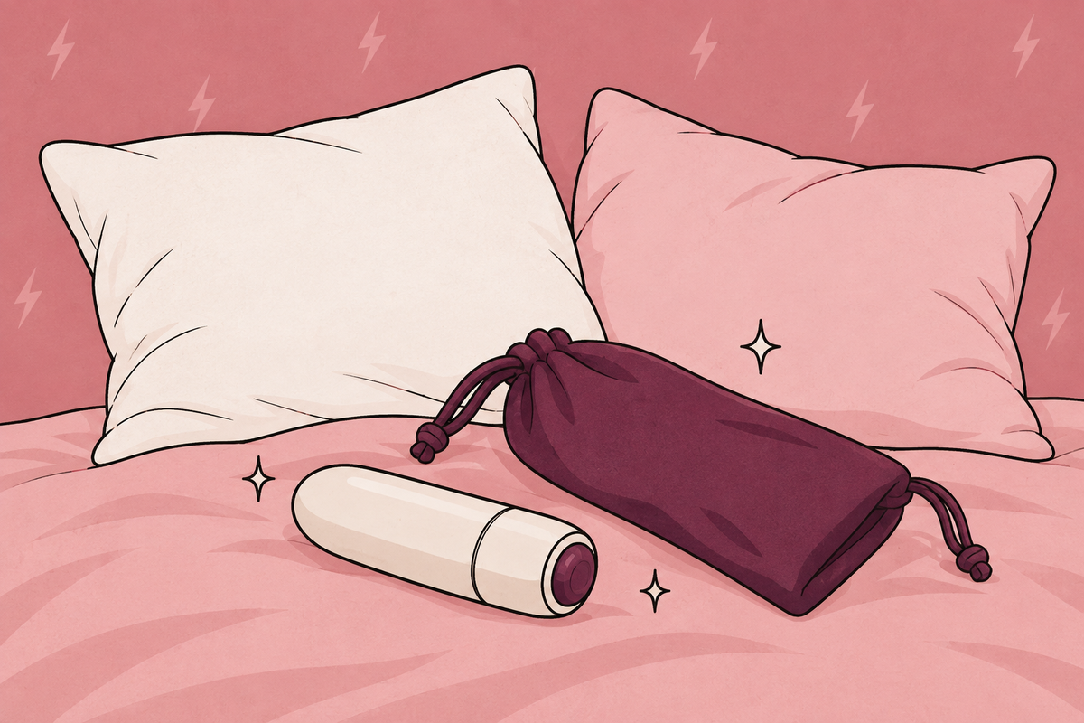 Illustration of pillows, a bullet vibrator and a storage pouch on a bed.